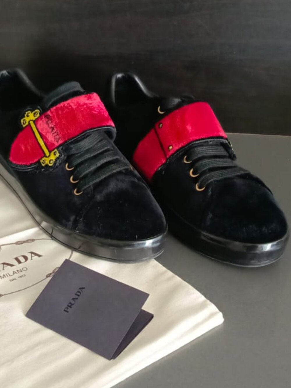 Prada sneakers in black velvet with bold red straps.